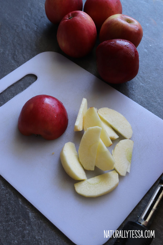 Fuji apples peeled and cored on top of a gray slate and cutting board