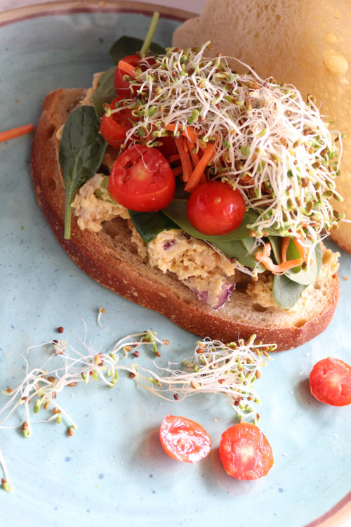 Chickpea salad sandwich with tomatoes, sprouts, and carrots by Naturally Tessa